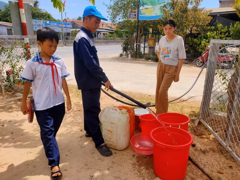 Học sinh ở xã Chân Mây - Lăng Cô tranh thủ ngoài giờ học đi hứng từng xô nước từ xe bồn của HueWACO. Ảnh NL.
