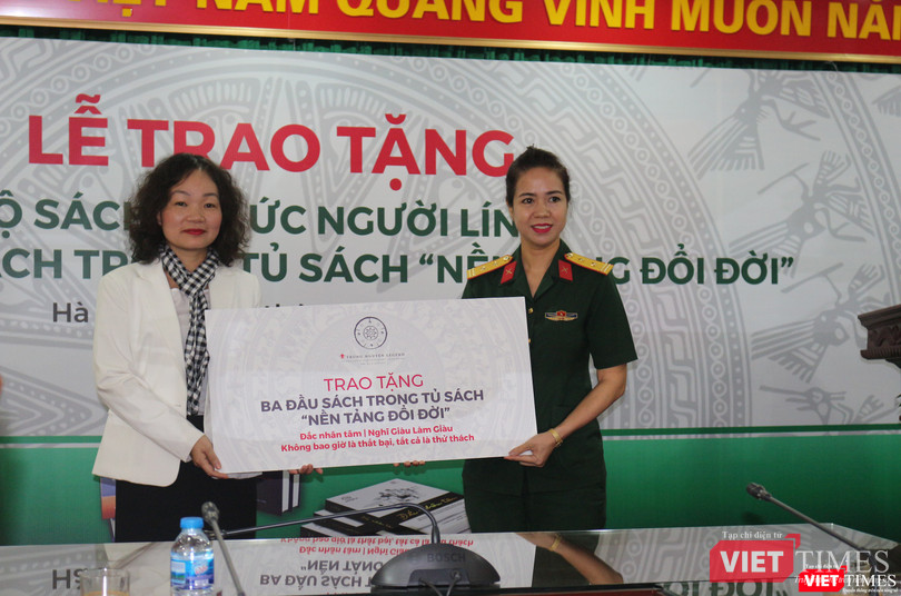 Bà Võ Thị Hà Giang - Giám đốc Truyền thông của Tập đoàn Trung Nguyên Legend trao tặng tượng trưng 3 đầu sách trong tủ sách "Nền tảng đổi đời" cho Trung tá Mạc Thùy Dương - Phó giám đốc Thư viện Quân đội