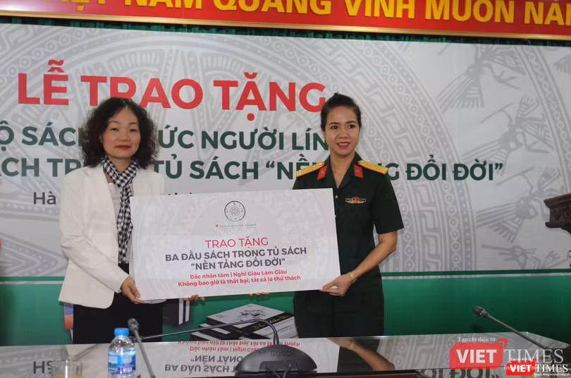 Bà Võ Thị Hà Giang - Giám đốc Truyền thông của Tập đoàn Trung Nguyên Legend trao tặng tượng trưng 3 đầu sách trong tủ sách "Nền tảng đổi đời" cho Trung tá Mạc Thùy Dương - Phó giám đốc Thư viện Quân đội