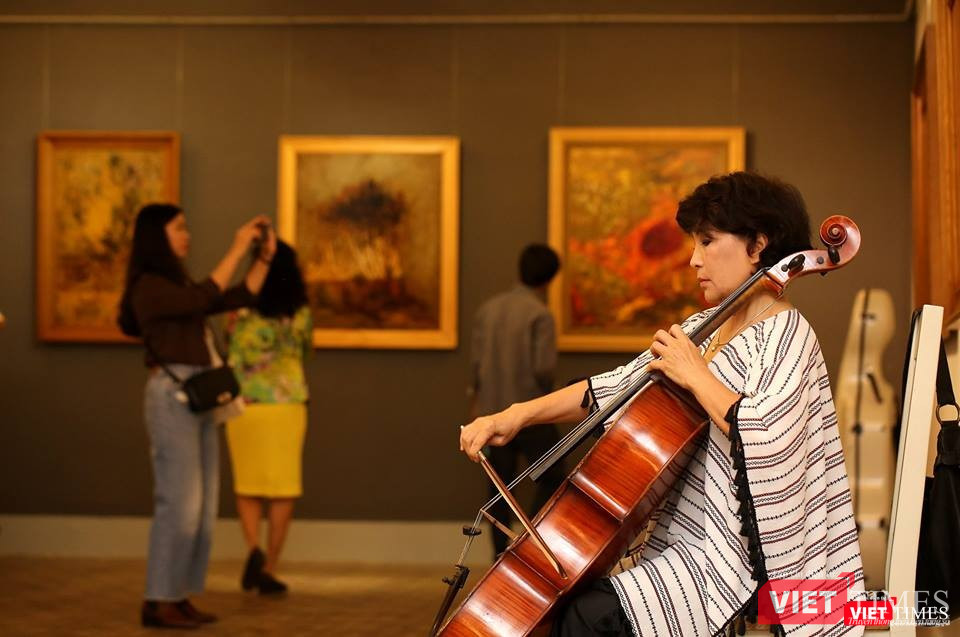 Nghệ sĩ chơi đàn tại buổi khai mạc triển lãm còn công chúng say sưa chiêm ngắm những bức tranh thuộc thể loại "nữ hoàng"