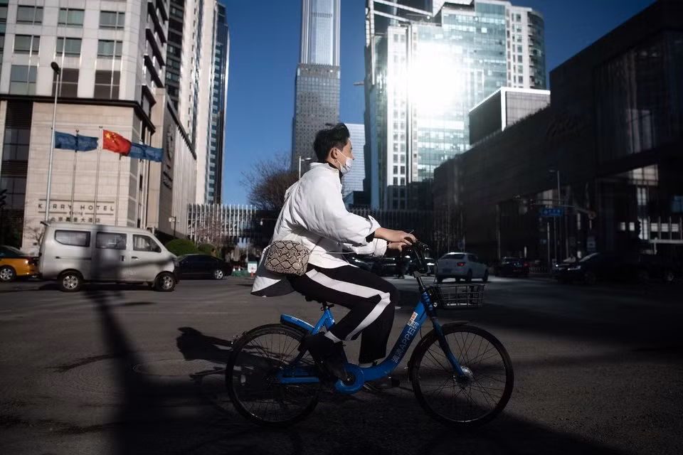 Một người đàn ông đang đạp xe trong khu thương mại trung tâm ở Bắc Kinh ngày 21/3/2019 (ảnh: AFP)