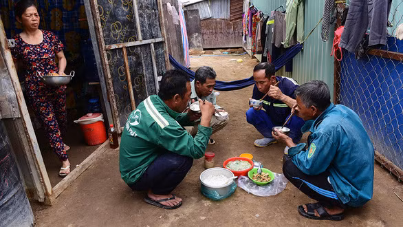 Bốn anh gồm Tấn Lợi, Lê Văn Cẩn, Ngô Văn Diến, Trần Văn Chiến, cùng quê Cà Mau lên TP.HCM làm công nhân tại các công trình xây dựng tại Thủ Thiêm, quận 2. Họ sống trong các lều trại dành cho công nhân gần công trình. Trong ảnh: 4 anh ăn cơm trưa tại khu lều trại sau khi đi làm về - Ảnh: QUANG ĐỊNH