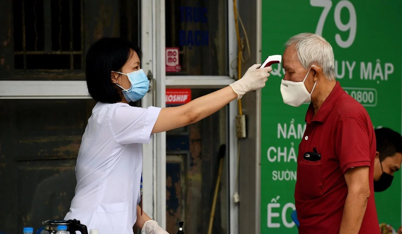 Một nhân viên y tế đeo khẩu trang kiểm tra nhiệt độ của một người đàn ông ở Hà Nội (ảnh AFP) Một nhân viên y tế đeo khẩu trang kiểm tra nhiệt độ của một người đàn ông ở Hà Nội (ảnh AFP)
