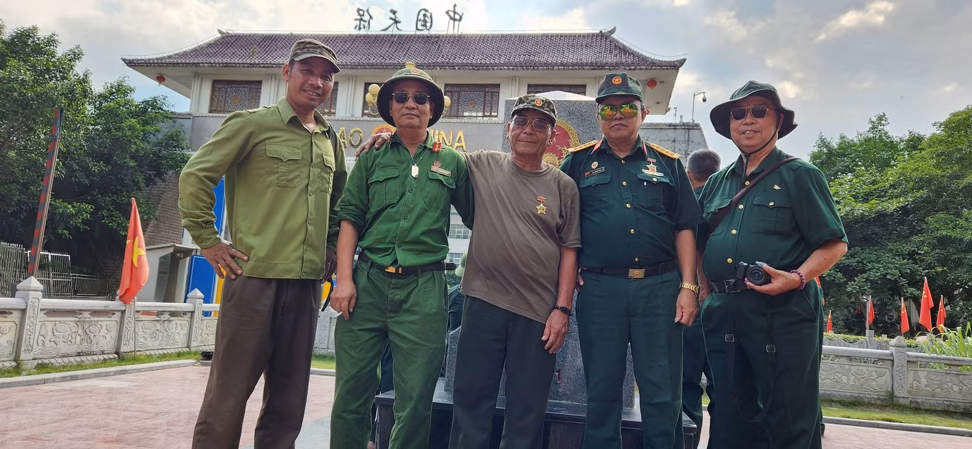 Trần Côn Sơn (thứ 2 trái qua) và Nguyễn Văn Hồng cùng đồng đội bên cạnh cột mốc ở Cửa khẩu Thanh Thủy, nơi khi xưa là chiến trường. Ảnh: Thu Thủy