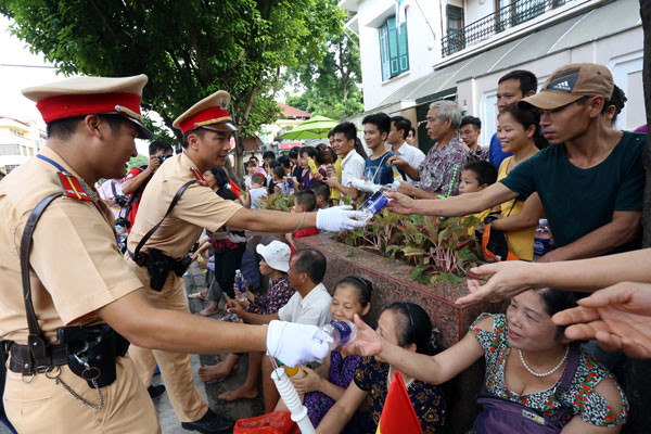 Cảnh sát chuyển nước uống cho người dân ngồi xem đoàn diễu binh trên phố Nguyễn Thái Học. Ảnh: Bá Đô.