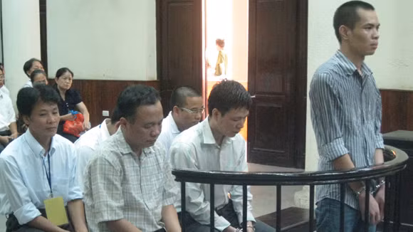 Lê Quang Khải (đứng) cùng đồng phạm trước vành móng ngựa tại phiên toà 