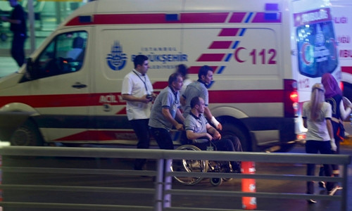 Nhân viên y tế hỗ trợ một người ngồi xe lăn rời khỏi sân bay Ataturk. Ảnh: Reuters.