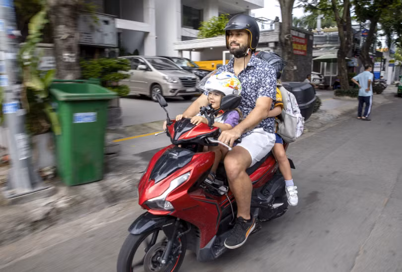 Vinnie Lauria chở con đi học bằng xe máy tại TP.HCM (Nguồn: Bloomberg)