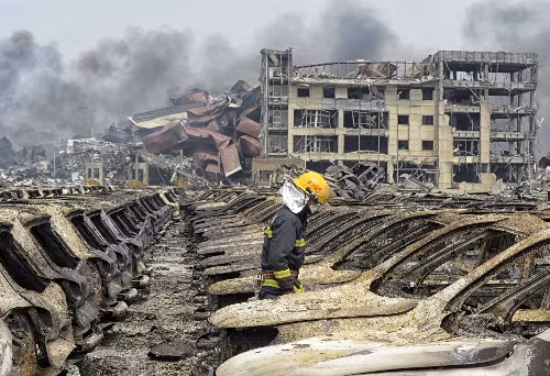 Lính cứu hỏa đi giữa các phương tiện bị phá hủy trong vụ nổ hôm 12/8. Ảnh: Reuters