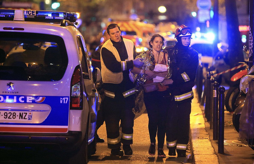 Nhân viên cứu hộ đang giúp một phụ nữ sau vụ xả súng ở nhà hát Bataclan, Paris đêm 13-11. Ảnh: Reuters.