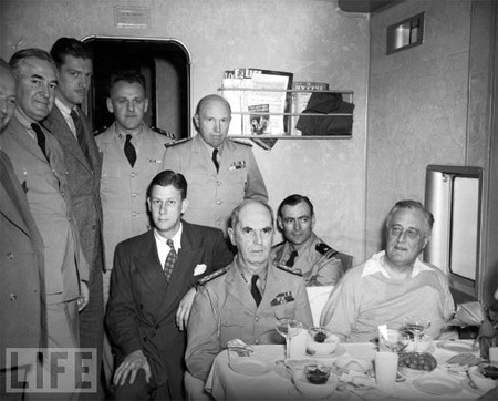 TT Franklin Delano Roosevelt (ngoài cùng bên phải) đón sinh nhật lần thứ 61 của ông trên máy bay từ Trinidad tới Miami năm 1943. Trên máy bay có các điệp viên Elmer Hipsley (người để ria, đang đứng) và Guy Spaman (mặc bộ vest tối màu đang ngồi).