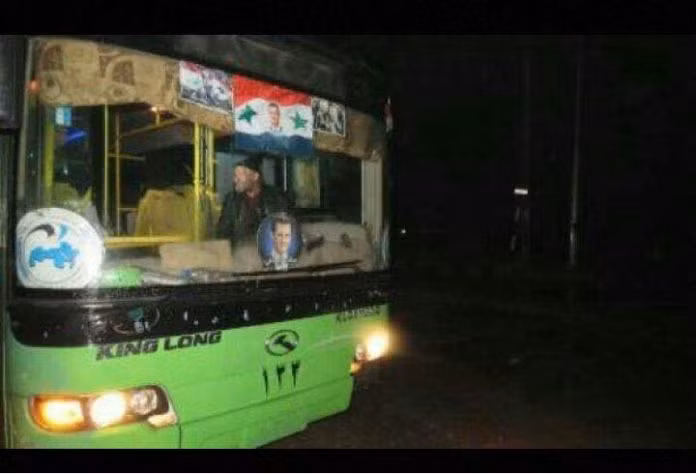 Xe buýt màu xanh của chính quyền Syria chở chiến binh thánh chiến lên đường về Idlib