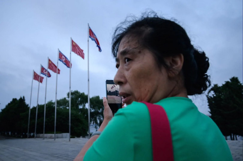 Một người phụ nữ sử dụng smartphone chụp ảnh quảng trường Kim Il Sung ở thủ đô Bình Nhưỡng (Ảnh: AFP)