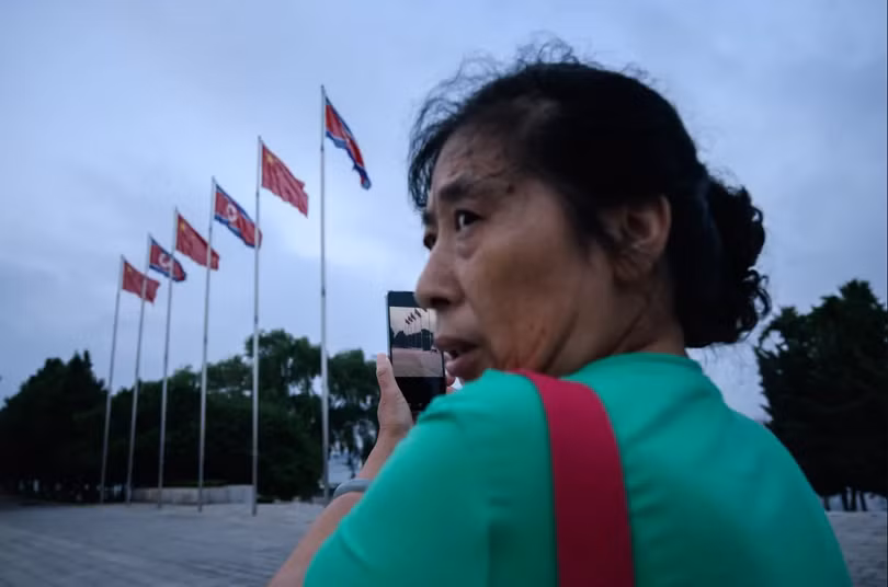Một người phụ nữ sử dụng smartphone chụp ảnh quảng trường Kim Il Sung ở thủ đô Bình Nhưỡng (Ảnh: AFP)