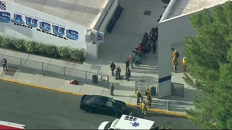 Cảnh sát vũ trang hộ tống một nhóm học sinh ra khỏi trường an toàn (Ảnh: CNN)