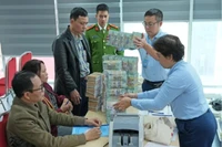 Người dân được nhân viên ngân hàng hỗ trợ nhận tiền bồi thường, hỗ trợ, tái định cư do phải di dời để thực hiện dự án làm quảng trường, công viên phía Đông hồ Hoàn Kiếm. Ảnh: Trọng Phú