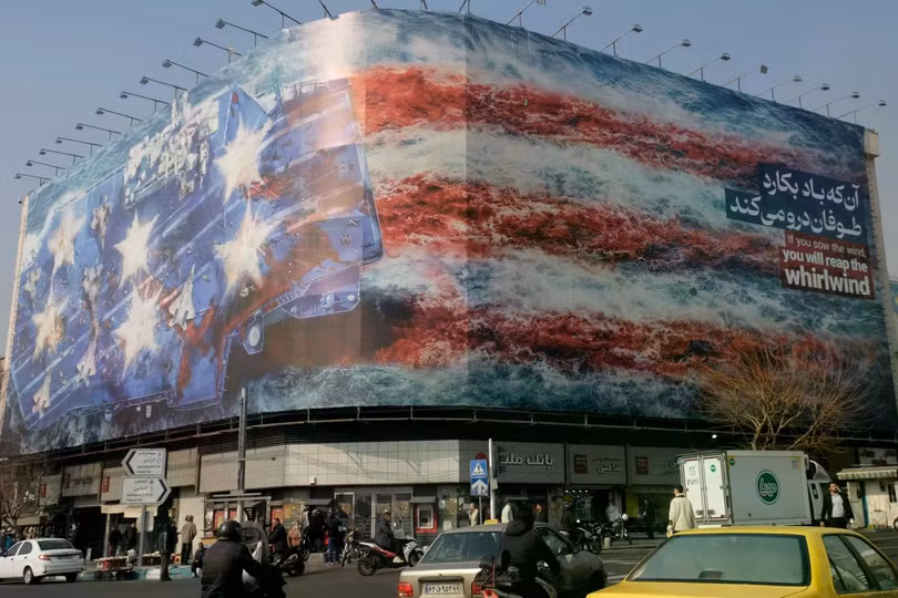 Một biểu ngữ khổng lồ được trưng bày tại Quảng trường Cách mạng mô tả vụ tấn công tên lửa vào tàu sân bay của Mỹ, được sơn màu cờ Mỹ vào ngày 26/1 tại Tehran, Iran. Ảnh: Newsweek.