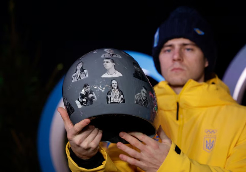 Vận động viên Vladyslav Heraskevych của Ukraine giơ cao chiếc mũ bảo hiểm đặc biệt tại một cuộc họp báo. Ảnh: Reuters.