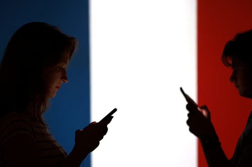 Bức ảnh minh họa cho thấy các thiếu niên tạo dáng chụp ảnh với điện thoại thông minh trên tay trước lá cờ Pháp. Ảnh: Reuters.