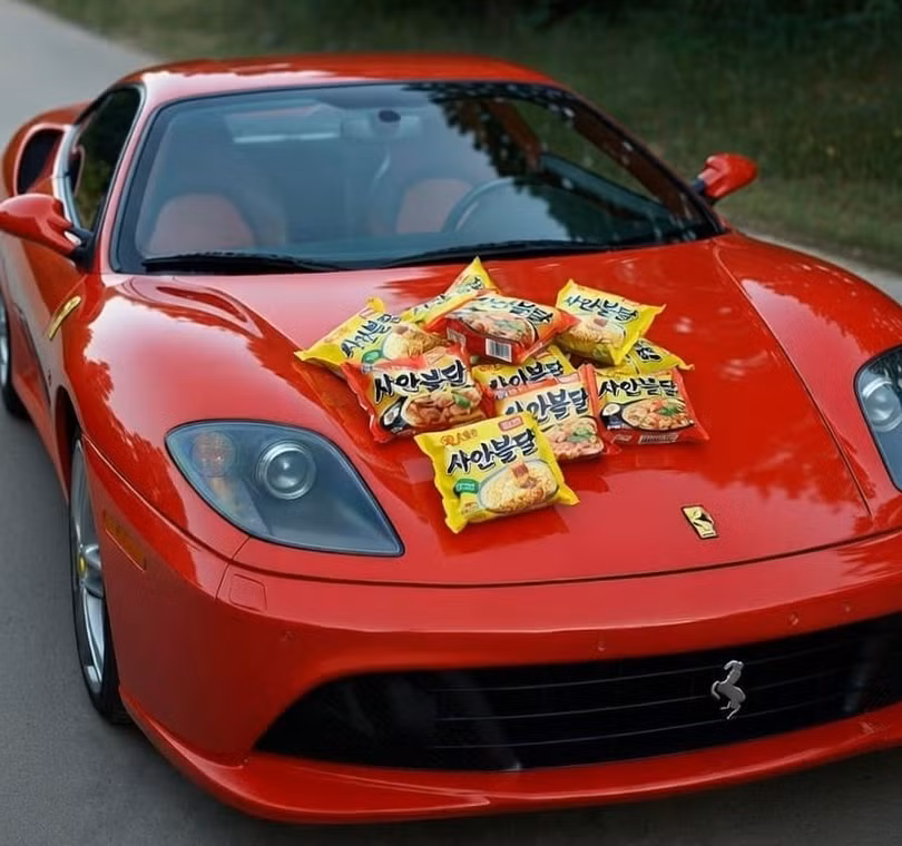 Những gói mì có giá phải chăng được đặt trên một chiếc Ferrari trong bức ảnh "thử thách nghèo đói" ở Hàn Quốc. Ảnh: OC.