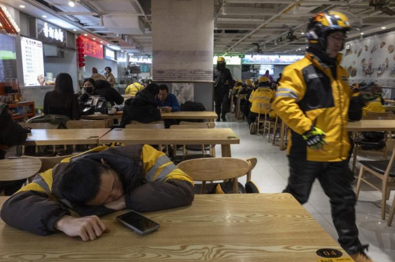 Một nhân viên giao hàng ở Trung Quốc tranh thủ nghỉ ngơi sau giờ cao điểm ăn trưa. Ảnh: WSJ.