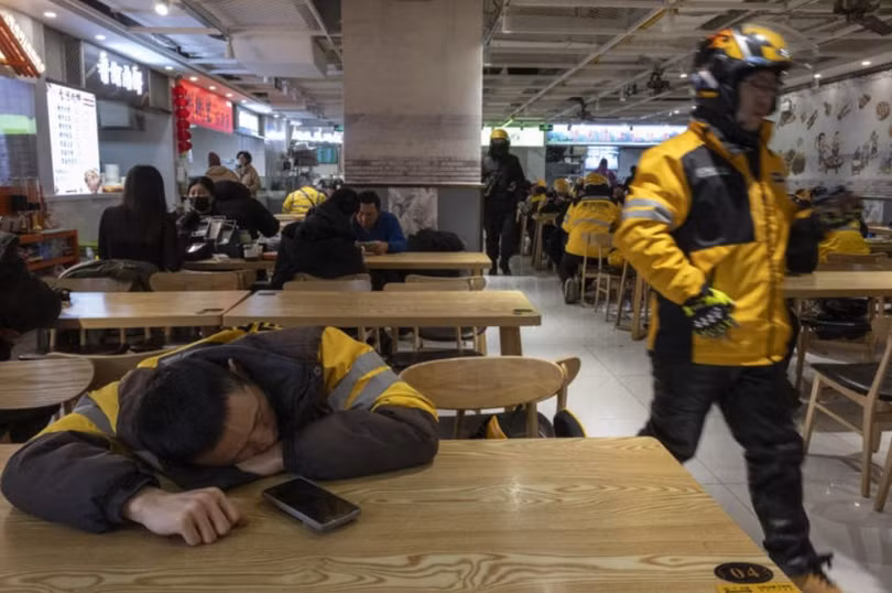 Một nhân viên giao hàng ở Trung Quốc tranh thủ nghỉ ngơi sau giờ cao điểm ăn trưa. Ảnh: WSJ.