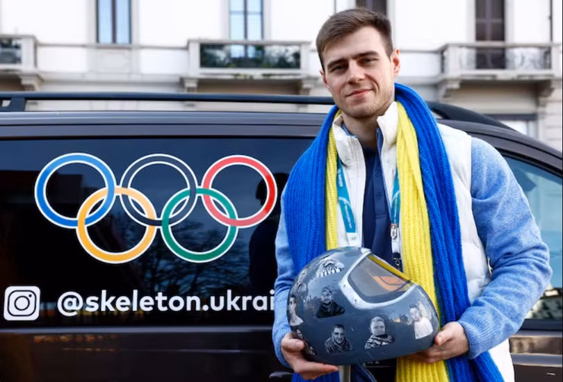 Vận động viên Ukraine Vladyslav Heraskevych chụp ảnh cùng chiếc mũ bảo hiểm sau khi bị truất quyền thi đấu. Ảnh: Reuters.