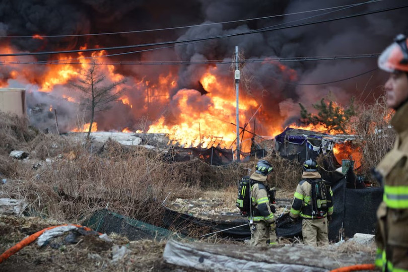 Ngày 16/1, các nhân viên cứu hỏa hướng mắt về phía đám cháy đang bao trùm làng Guryong, khu ổ chuột cuối cùng ở quận Gangnam, Seoul, Hàn Quốc. Ảnh: Reuters.