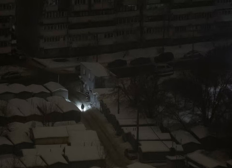 Một người dân ở Kiev dùng đèn pin soi đường khi mất điện sau đòn tấn công bằng tên lửa và UAV của Nga ngày 12/2. Ảnh: Reuters.