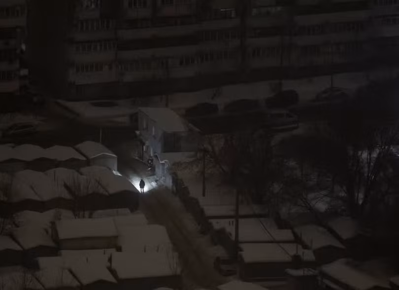 Một người dân ở Kiev dùng đèn pin soi đường khi mất điện sau đòn tấn công bằng tên lửa và UAV của Nga ngày 12/2. Ảnh: Reuters.