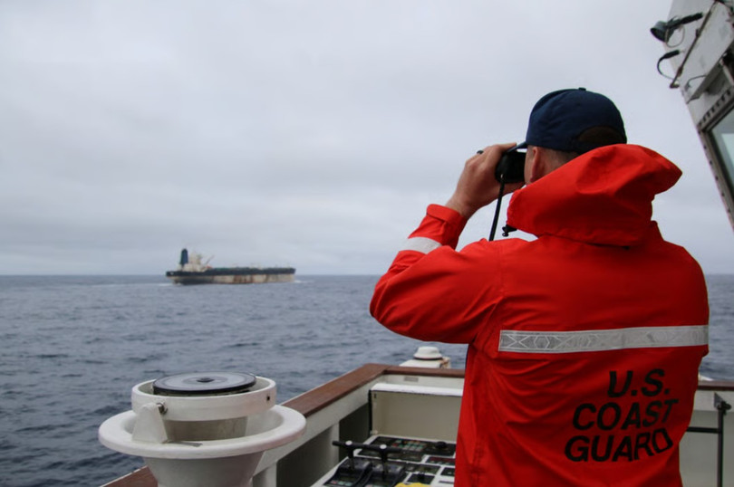 Một sĩ quan thuộc Lực lượng Bảo vệ bờ biển Mỹ đang quan sát qua ống nhòm tàu ​​chở dầu Bella 1 có liên hệ với Nga, vốn đã được đổi tên thành Marinera. Ảnh: Reuters.