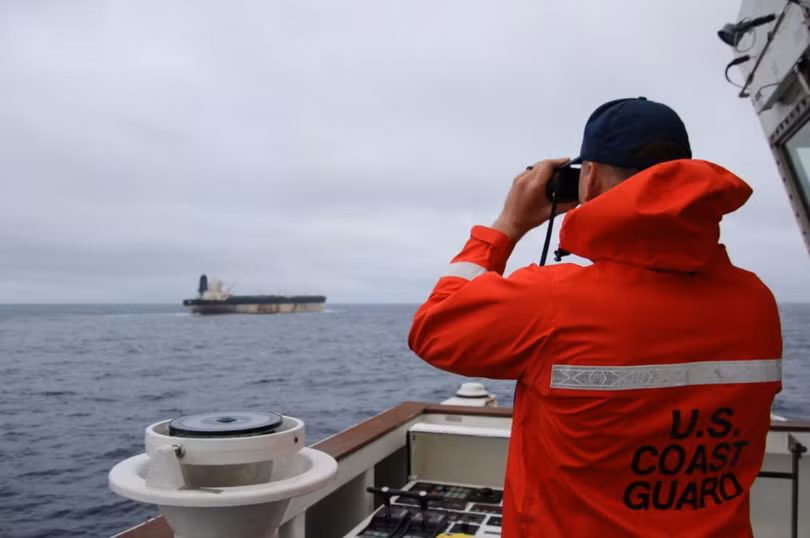 Một sĩ quan thuộc Lực lượng Bảo vệ bờ biển Mỹ đang quan sát qua ống nhòm tàu ​​chở dầu Bella 1 có liên hệ với Nga, vốn đã được đổi tên thành Marinera. Ảnh: Reuters.