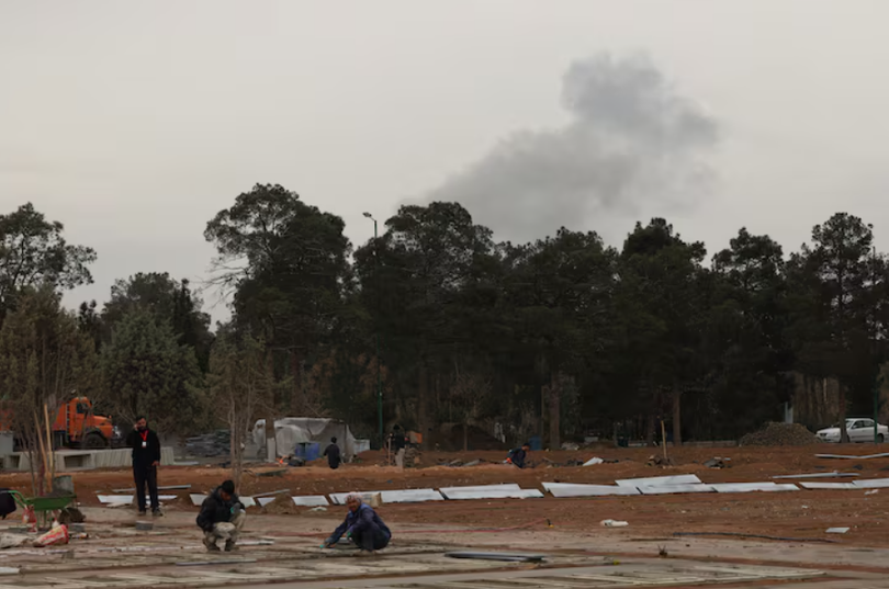 Người dân đang làm việc trong quá trình mở rộng nghĩa trang, trong khi khói bốc lên sau các cuộc không kích phía sau nghĩa trang Behesht-e Zahra ở Tehran, Iran ngày 16/3. Ảnh: Reuters.