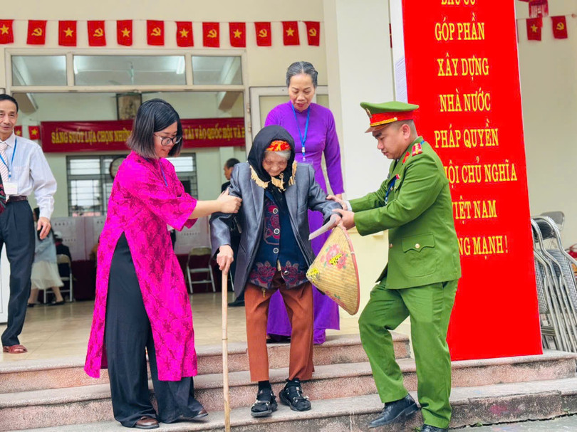 Cán bộ tổ bầu cử ở Hà Nội giúp cụ bà di chuyển sau khi bỏ phiếu. 