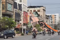 Người dân đi xe máy qua một tòa nhà bị đổ sập sau trận động đất ở Mandalay, Myanmar hôm 28/3. Ảnh: Reuters.