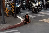 Một người phụ nữ được chụp ảnh đang chui ra khỏi một lỗ thoát nước dọc theo một con phố ở thành phố Makati, Philippines. Ảnh: William Roberts.