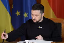 Tổng thống Ukraine Volodymyr Zelensky đang ký vào một cuốn sổ lưu bút. Ảnh: Getty.