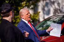 Tổng thống Donald Trump cầm tờ tiền có ghi giá xe Tesla trên đó. Ảnh: Getty.