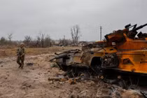 Một binh sĩ Ukraine kiểm tra xác xe thiết giáp của quân đội Nga gần Kiev (Ảnh: Reuters)