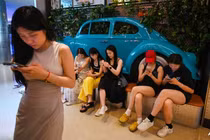 Người dân sử dụng điện thoại di động khi chờ chỗ trong một nhà hàng ở khu thương mại trung tâm Bắc Kinh ngày 11/7 (Ảnh: AFP)