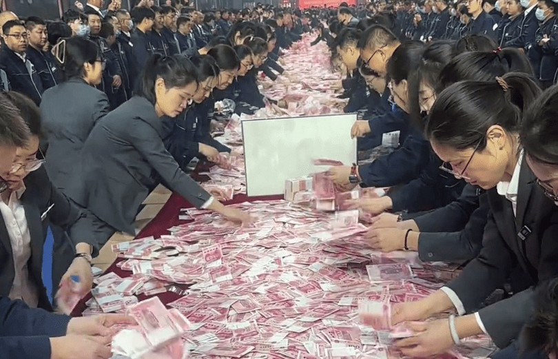 Các nhân viên được thưởng đua nhau đếm tiền để mang về. Ảnh: Singtao.