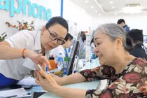 Bà Trương Thị Kim Huệ (72 tuổi) được nhân viên VinaPhone hướng dẫn tra cứu thông tin thuê bao trong ứng dụng VNeID.