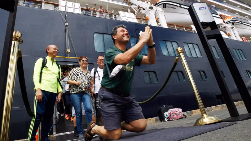 Một hành khách không kìm nén được sự sung sướng khi được lên bờ sau nhiều ngày lênh đênh trên biển (Ảnh: AP)