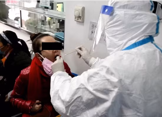Nhân viên y tế tại Bệnh viện Hiệp Hòa, Vũ Hán dùng que gạc lấy mẫu dịch ở họng của bệnh nhân để xét nghiệm virus Corona mới (Ảnh: Guancha).