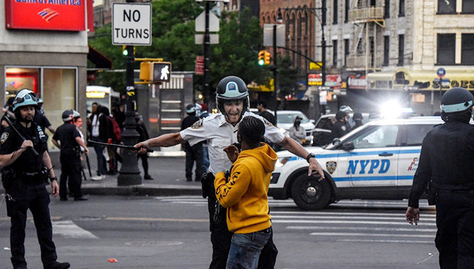 Cảnh sát yêu cầu một thiếu niên tuân thủ lệnh giới nghiêm sau 20h ở khu Bronx, New York (Ảnh: New York Times)