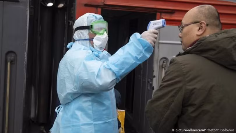 Nhân viên y tế Nga kiểm tra nhiệt độ của thương gia Trung Quốc (Ảnh: AP).