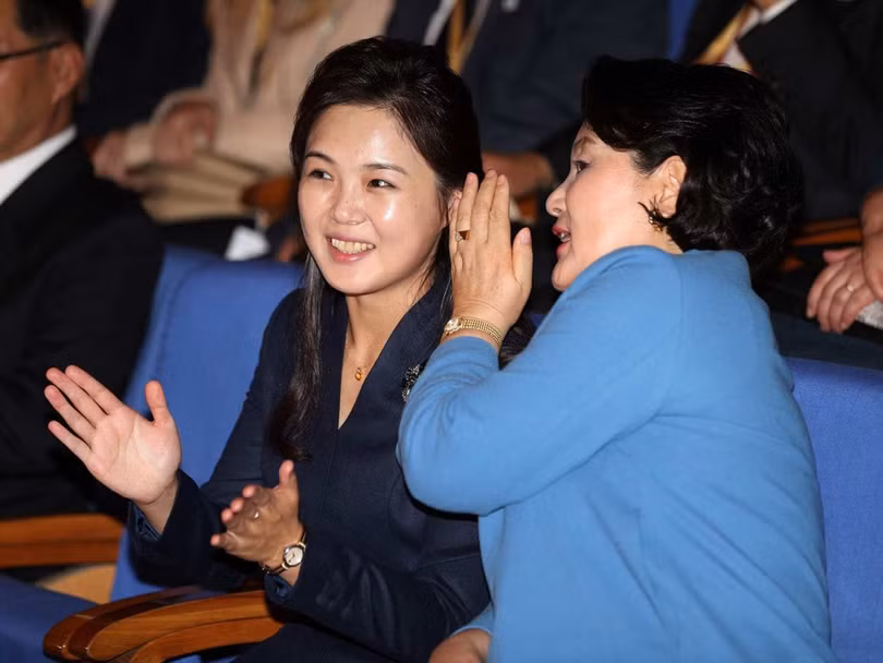 Cử chỉ thân mật của hai phu nhân khi xem biểu diễn văn nghệ