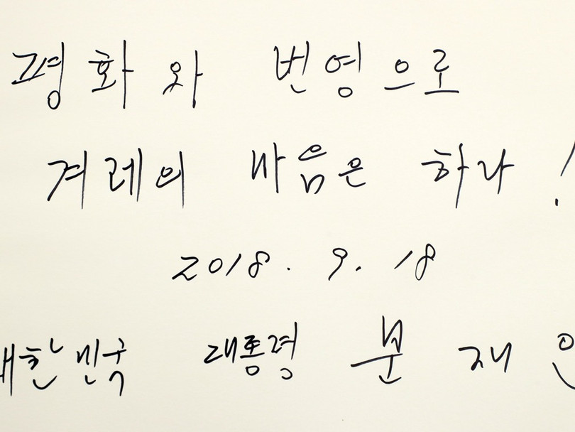 Ông Moon Jae In ghi trong sổ: "Hòa bình và phồn vinh, cả dân tộc đồng lòng. Tổng thống Đại Hàn Dân quốc Moon Jae In".