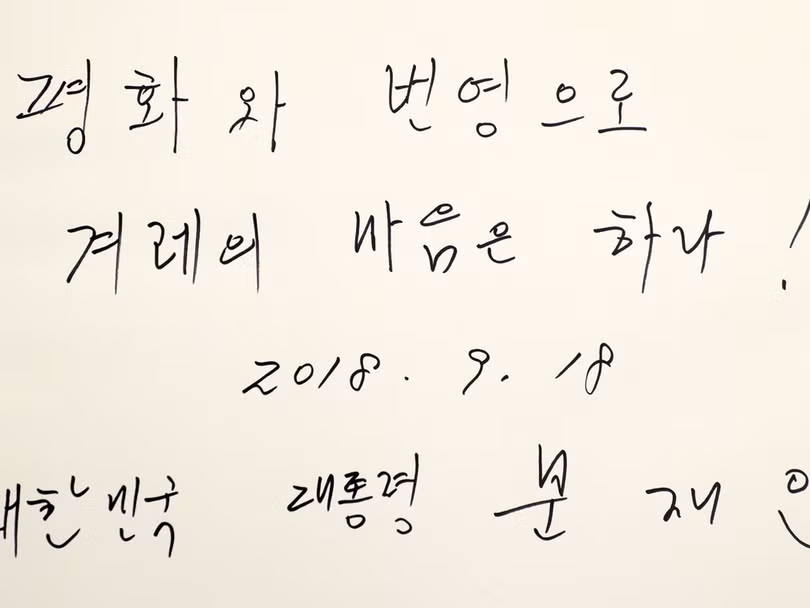 Ông Moon Jae In ghi trong sổ: "Hòa bình và phồn vinh, cả dân tộc đồng lòng. Tổng thống Đại Hàn Dân quốc Moon Jae In".