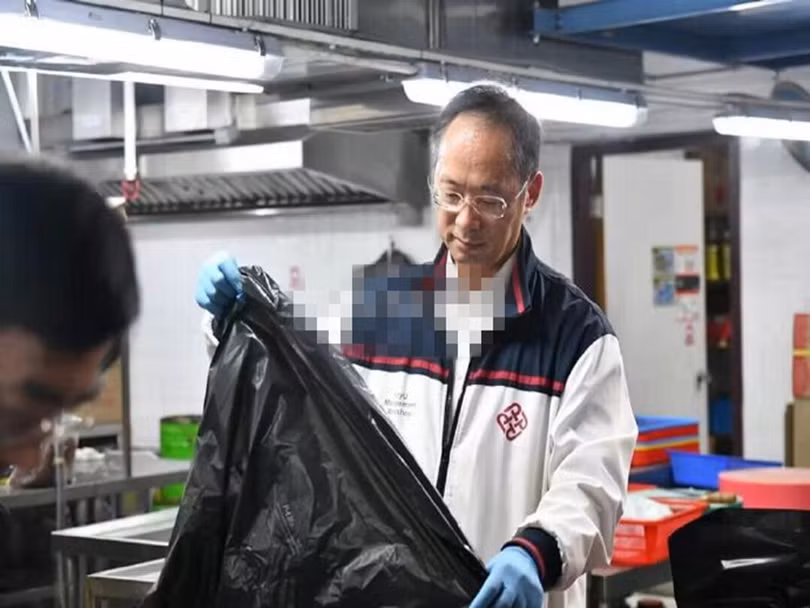 Ông Hiệu phó PolyU Vệ Bỉnh Giang dọn rác trong bếp ăn nhà trường.